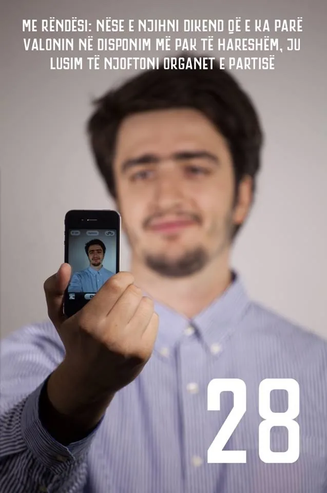 My Partia e Fortë candidate poster, number 28: me holding up a phone taking a selfie of myself, under the line asking people to notify the party if they ever see Valon looking less than cheerful.