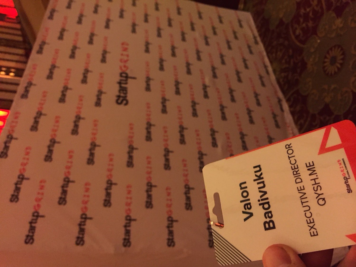 My conference badge in front of a Startup Grind step-and-repeat wall: "Valon Badivuku, Executive Director, QYSH.ME."