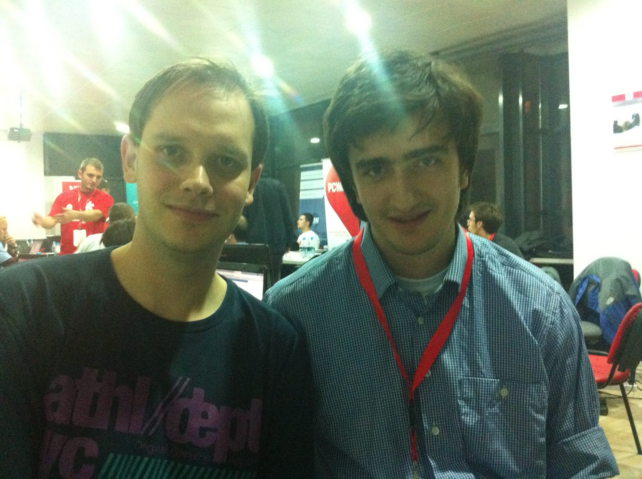 Me standing next to Peter Sunde on the event floor, with participants at laptops and sponsor banners behind us.
